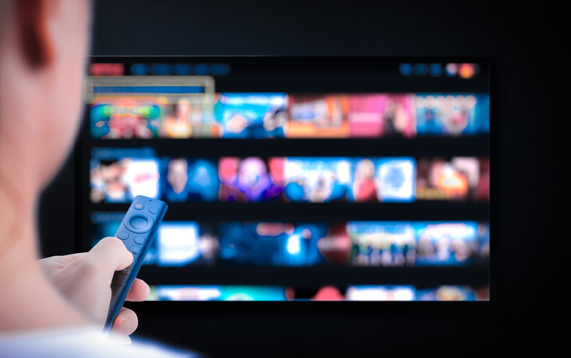 Multimedia streaming concept. Hand holding remote control. TV screen with lot of pictures. Television streaming. VoD content provider. Video service with internet streaming multimedia shows, series.